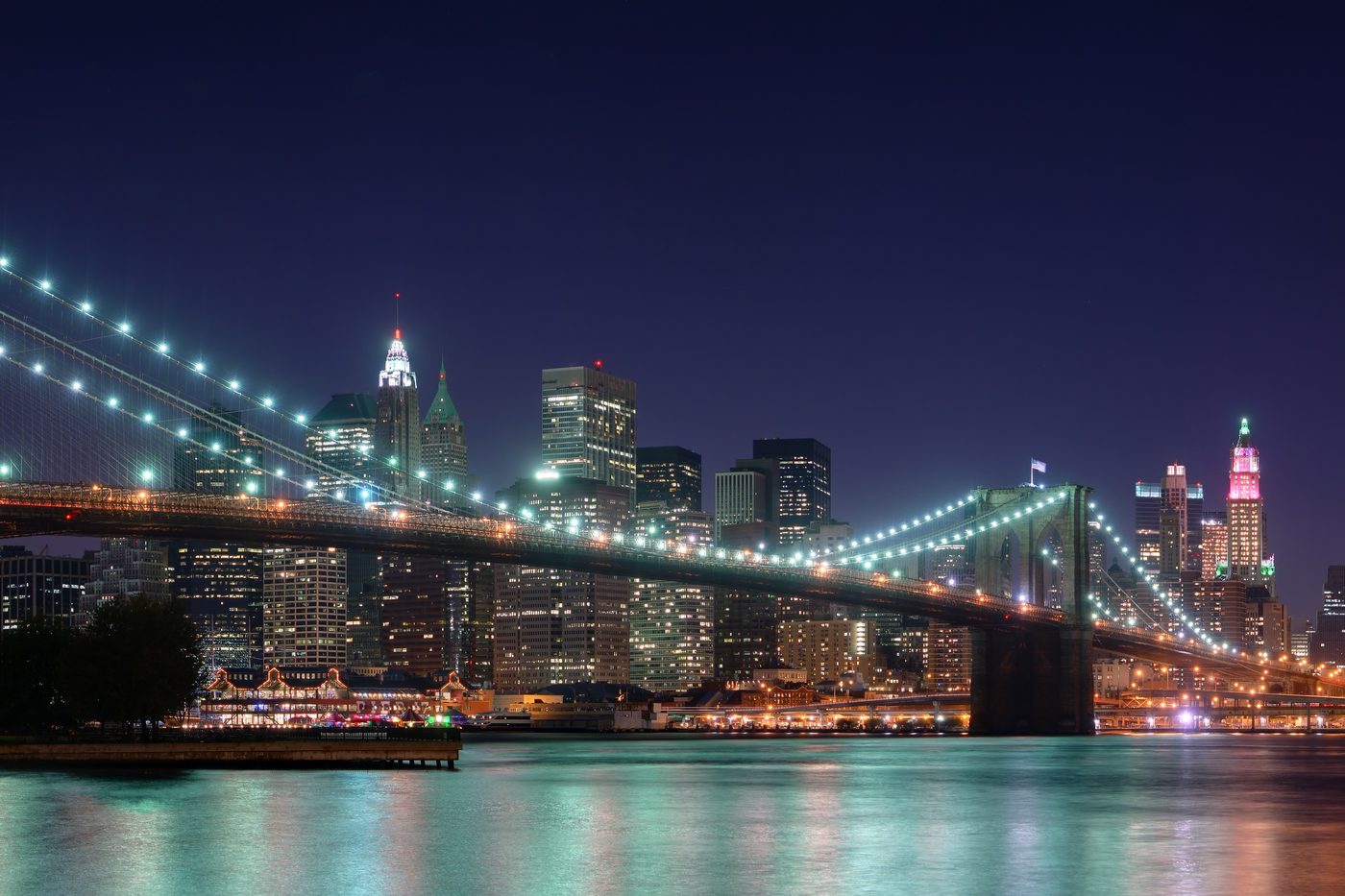 The Brooklyn Bridge lit at night, with the Lower Manhattan skyline beyond